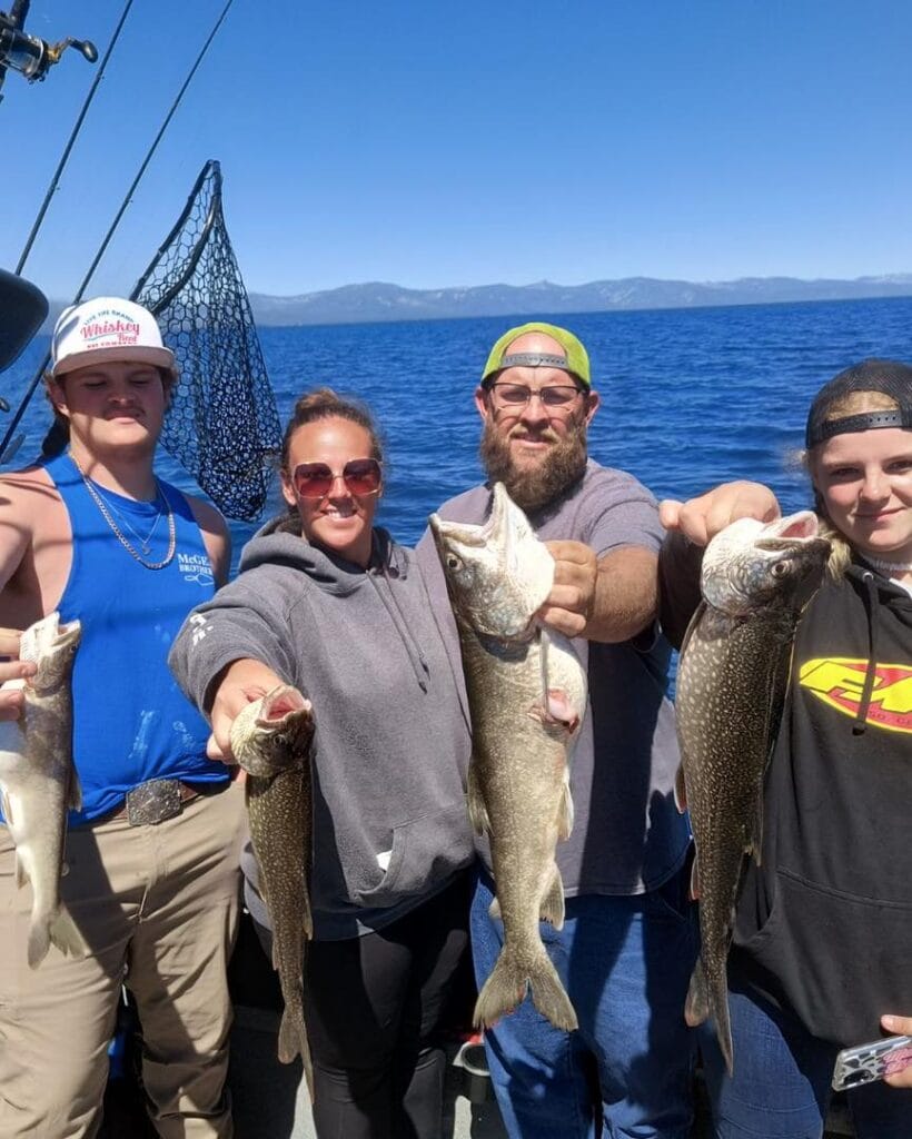 Group holding freshly caught Lake Trout on Lake Tahoe fishing charter