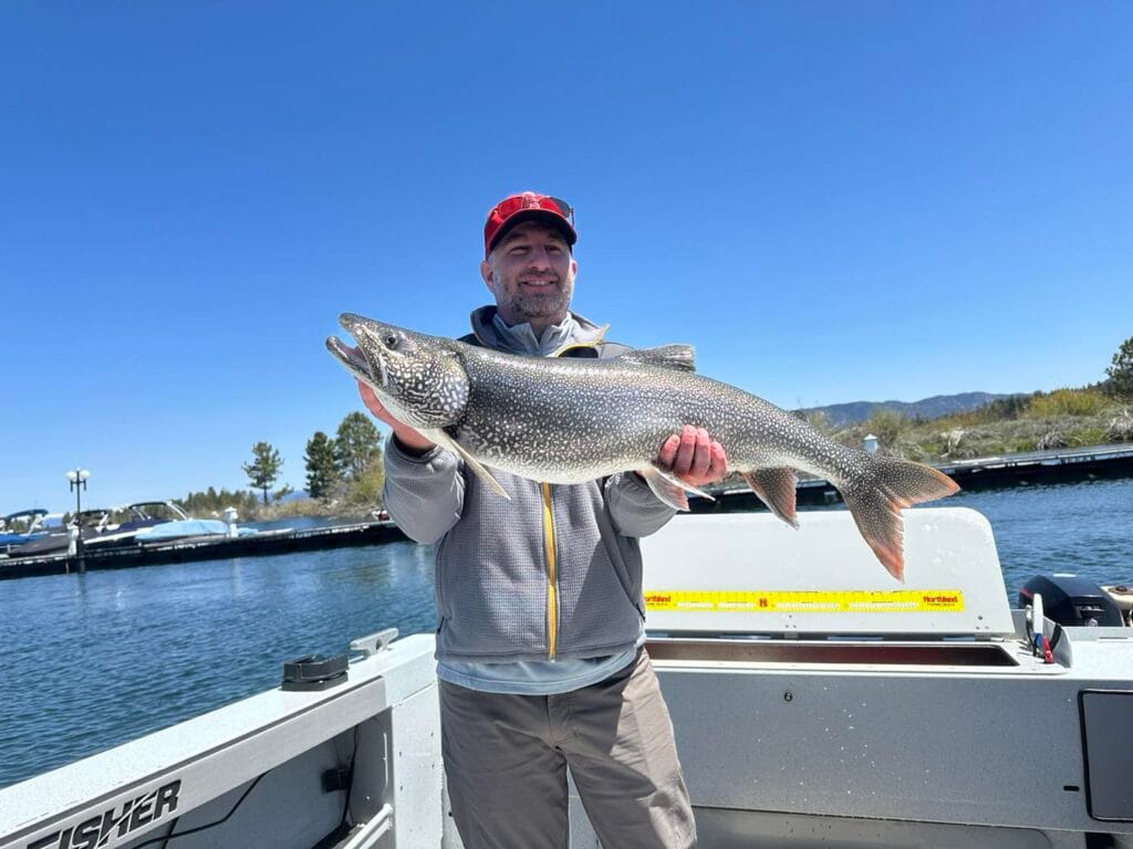 Angler holding large Lake Trout at Lake Tahoe marina during morning charter