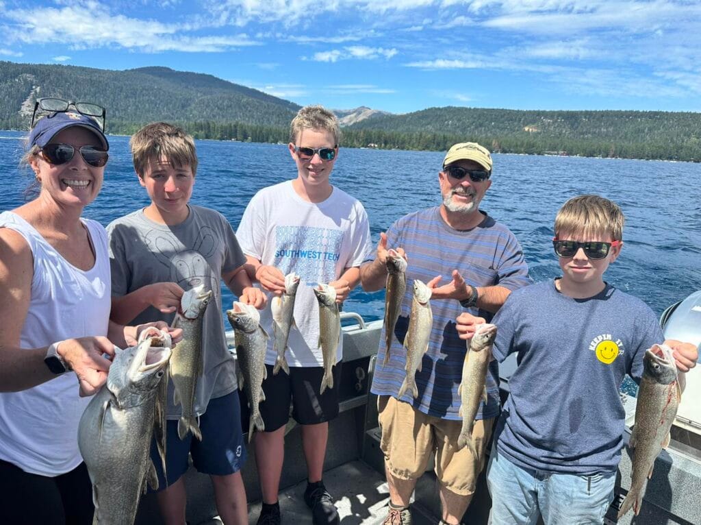 Family fishing on Lake Tahoe charter holding trout catches with smiles.