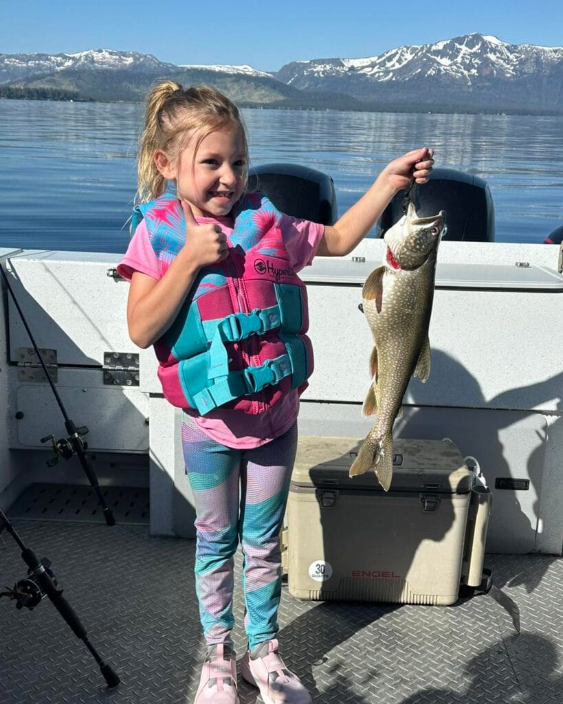 Young girl proudly holding Lake Trout on Lake Tahoe fishing trip