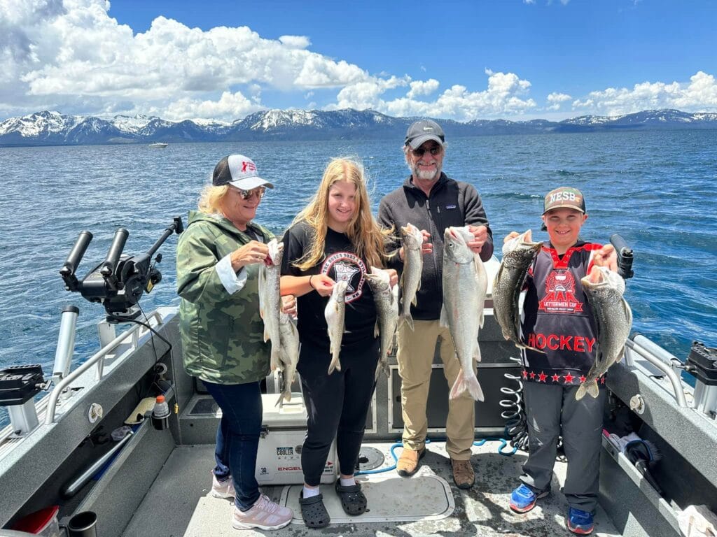 Four anglers holding Lake Trout under “Mile High” sign on FishTahoe.com charter