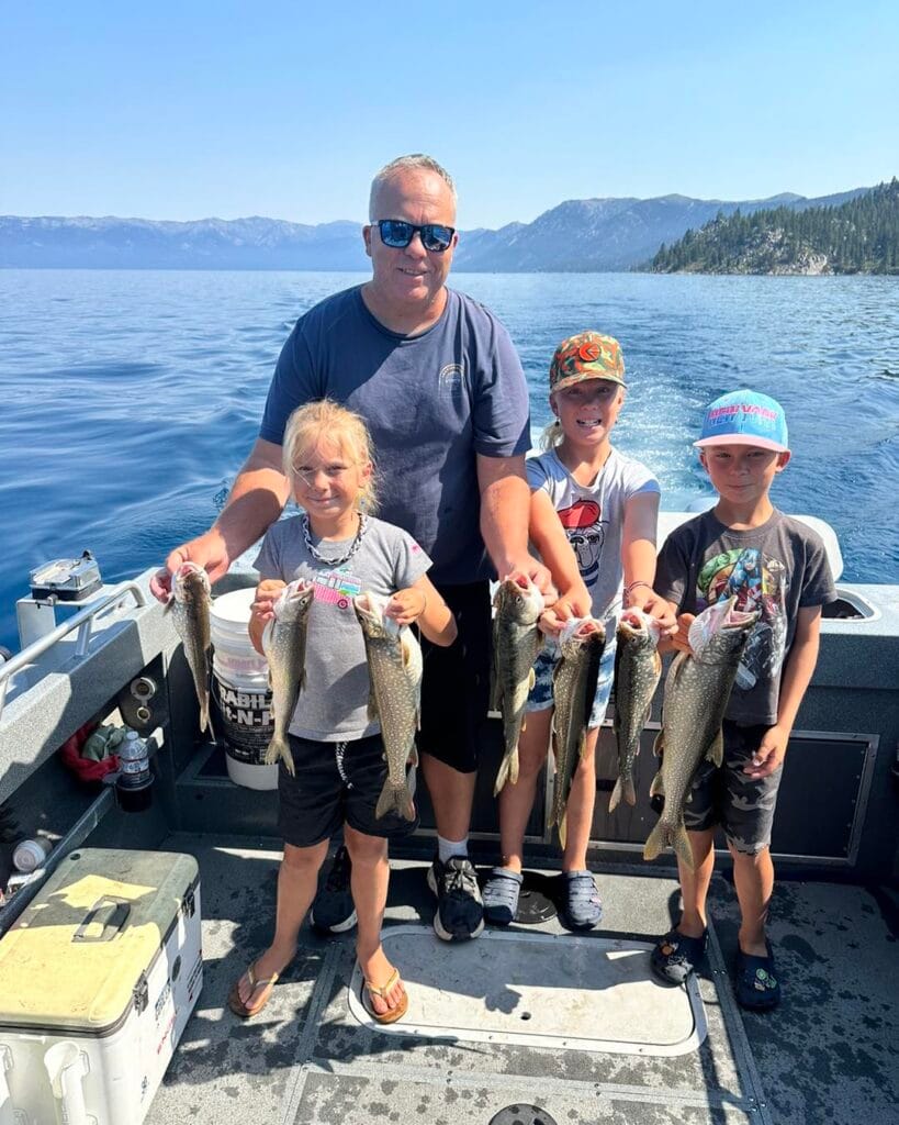 Father and three kids holding Lake Trout on Lake Tahoe charter boat