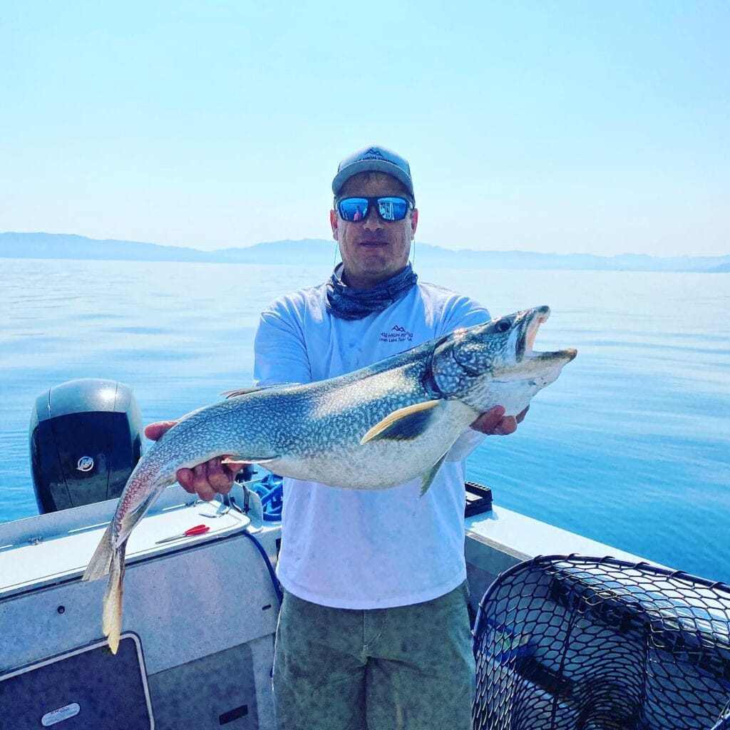 Fisherman holding trophy Lake Trout on calm morning charter with FishTahoe.com