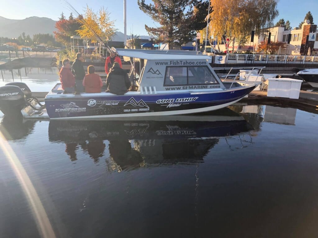 Fishing charter boat “Gone Fishin” docked at Lake Tahoe marina during sunrise.