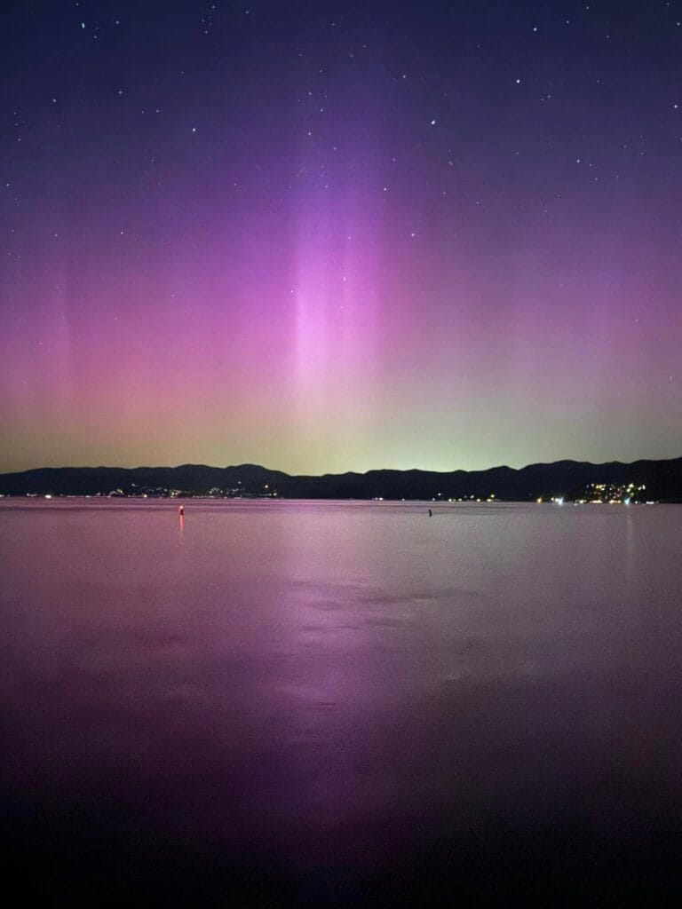 Northern Lights glowing above Lake Tahoe with mountain silhouette