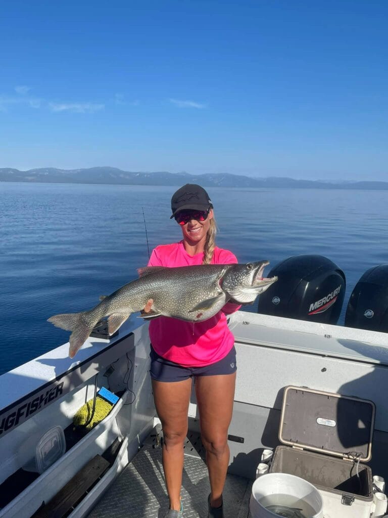 Woman holding a large Lake Trout on a Lake Tahoe fishing charter with FishTahoe.com