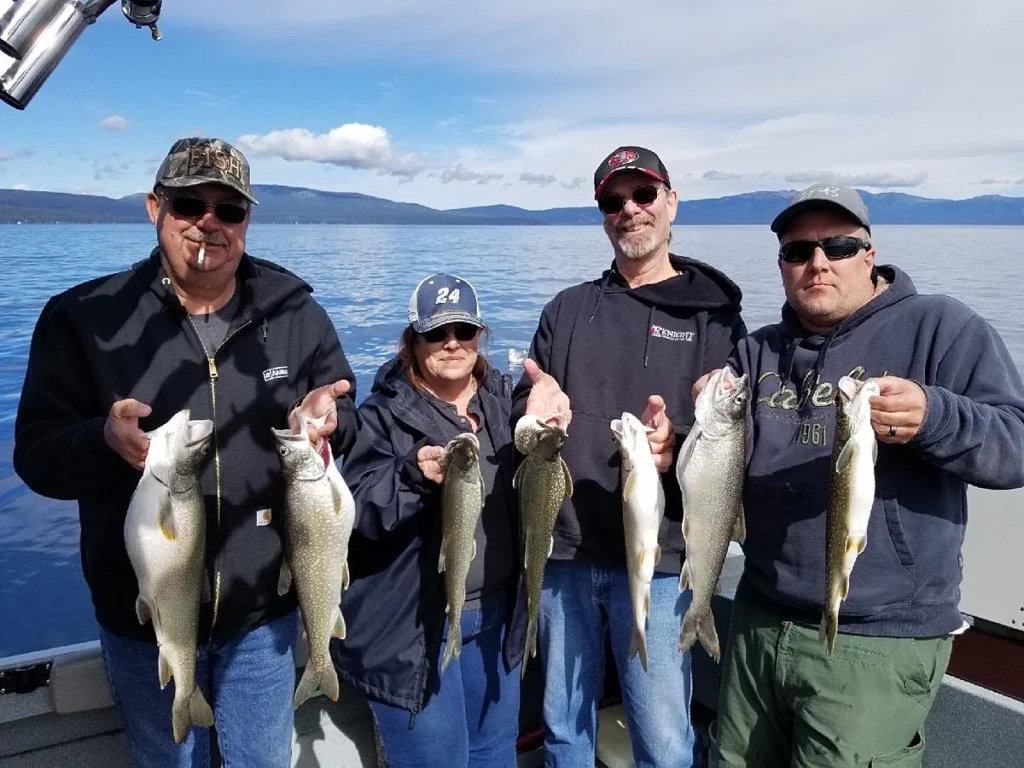 Group of anglers holding freshly caught lake trout during an October fishing trip on South Lake Tahoe with Mile High Fishing Charters.